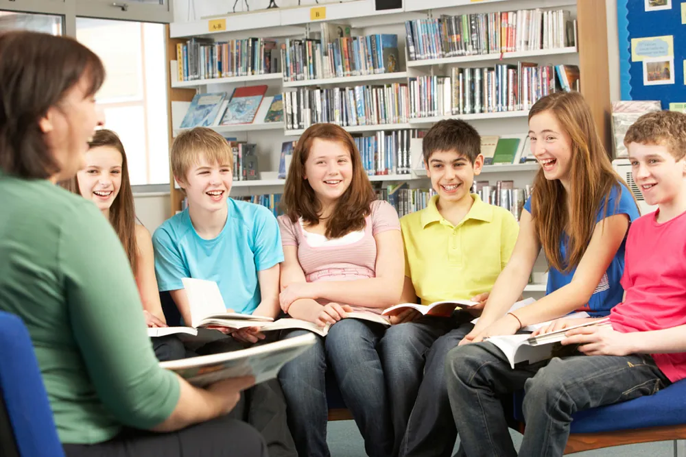 A group of teenagers reading together in the library